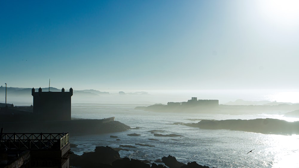 Silueta del faro en la cima de la colina junto al mar durante el día