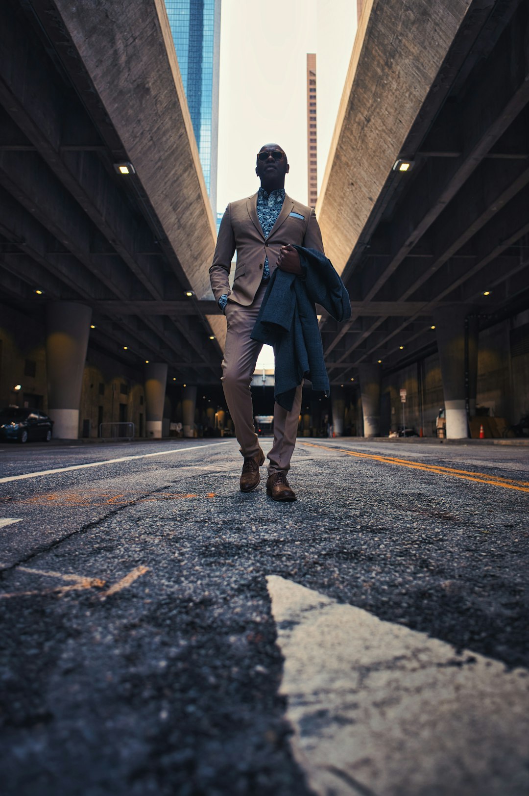 man in blue jacket and black pants walking on gray concrete road during daytime