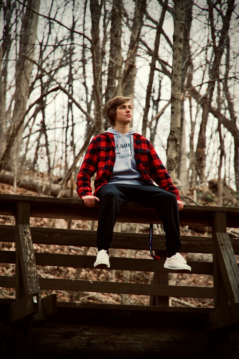 woman in red and black striped sweater sitting on brown wooden bench