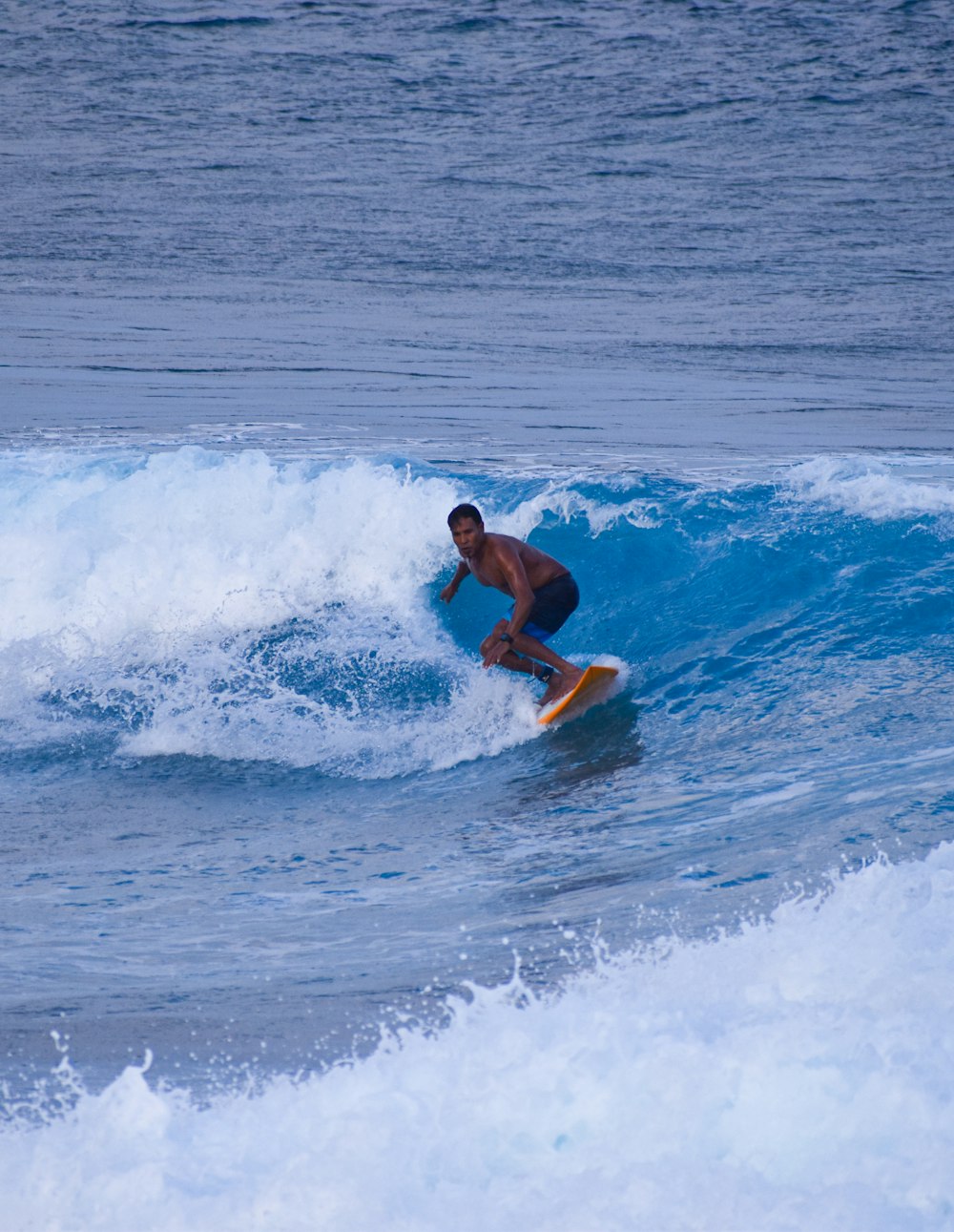 man in black shorts surfing on sea waves during daytime