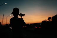 A dynamic shot of a camera operator capturing a bustling Douala cityscape at sunset.