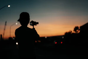 A candid moment of a traveler filming a sunset with Godox lighting equipment near the van.