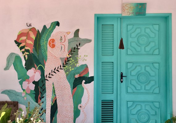 A mural beside a turquoise door in the village — Jericoacoara, Brazil