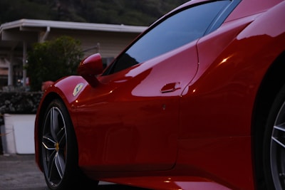 A bright red sports car with a flawless exterior finish parked in front of a modern home.