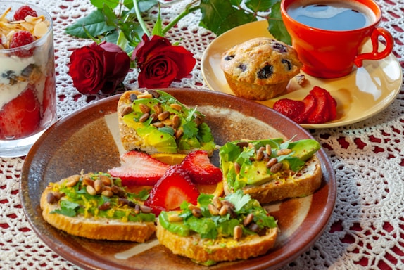 A vibrant display of avocado toast, berry parfait, and a steaming cup of coffee on a rustic wooden table.