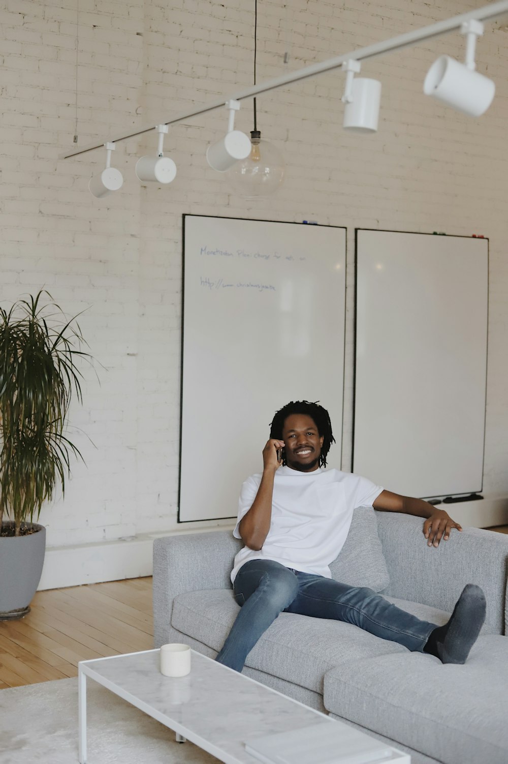 woman in white crew neck t-shirt and blue denim jeans sitting on gray couch