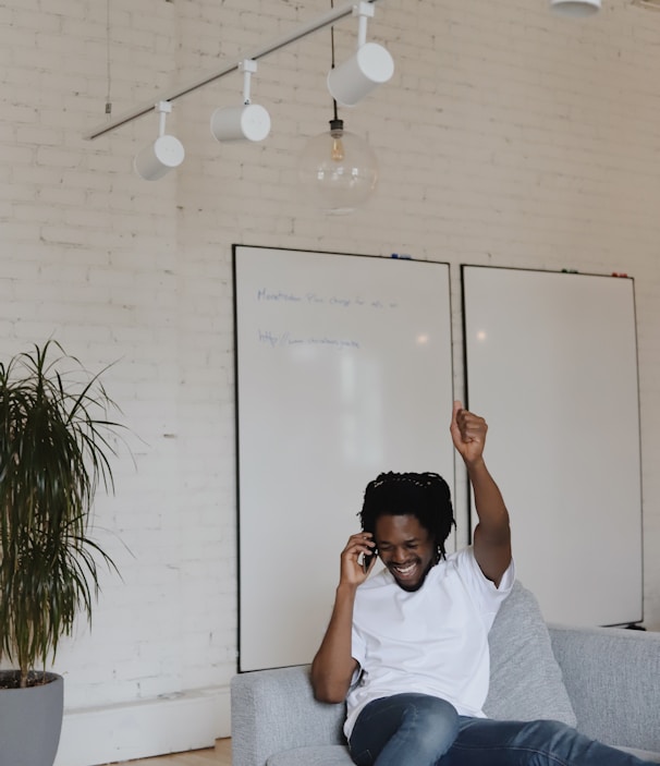 man in white crew neck t-shirt sitting on gray couch