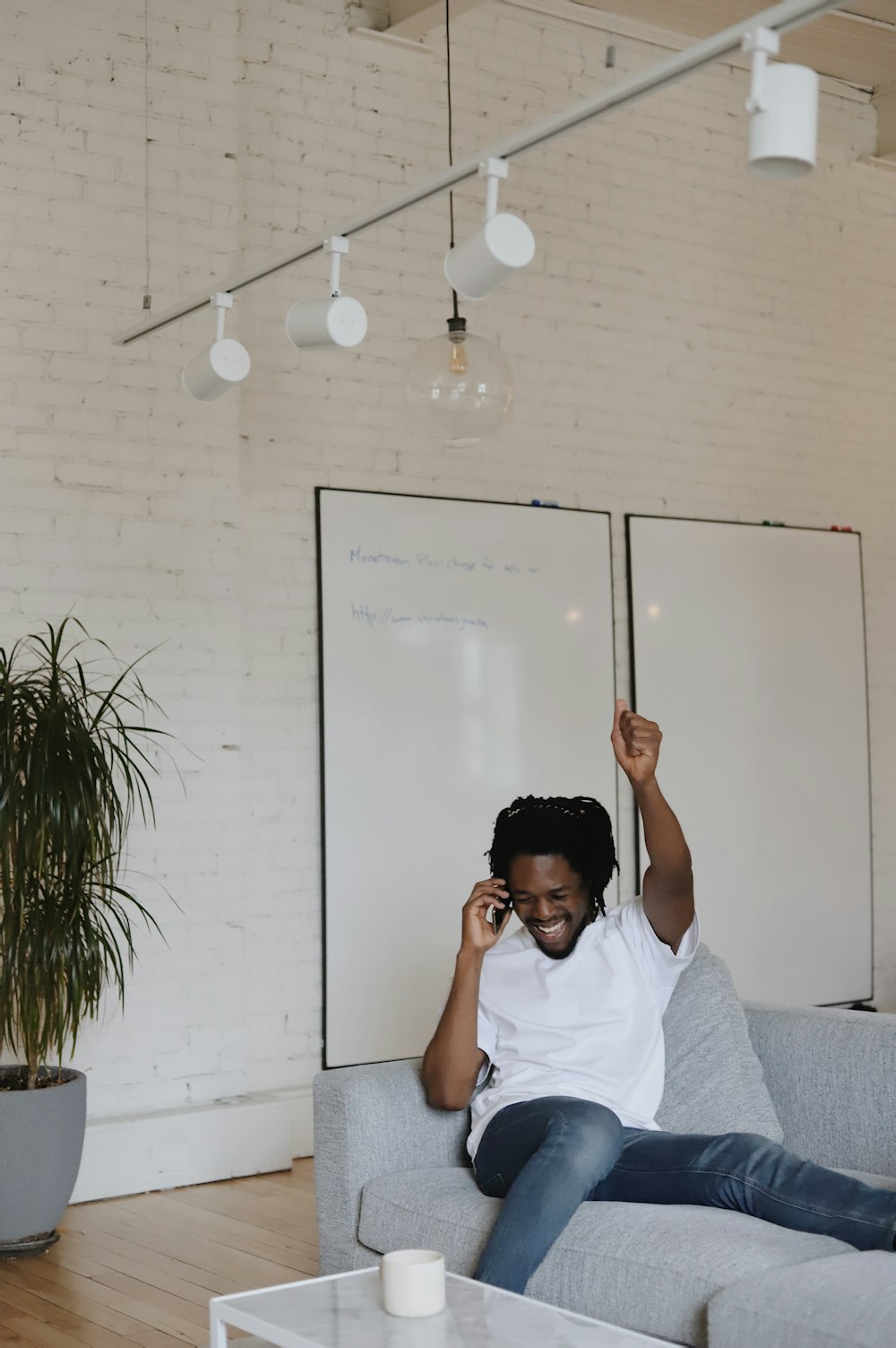 man in white crew neck t-shirt sitting on gray couch