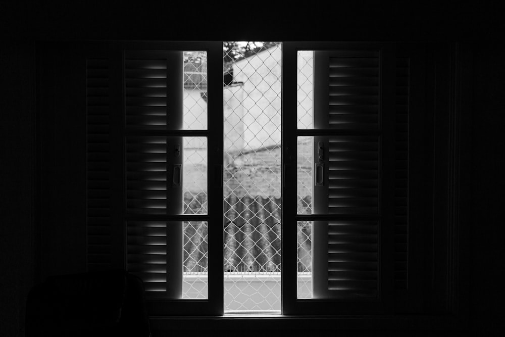 grayscale photo of window with metal grille