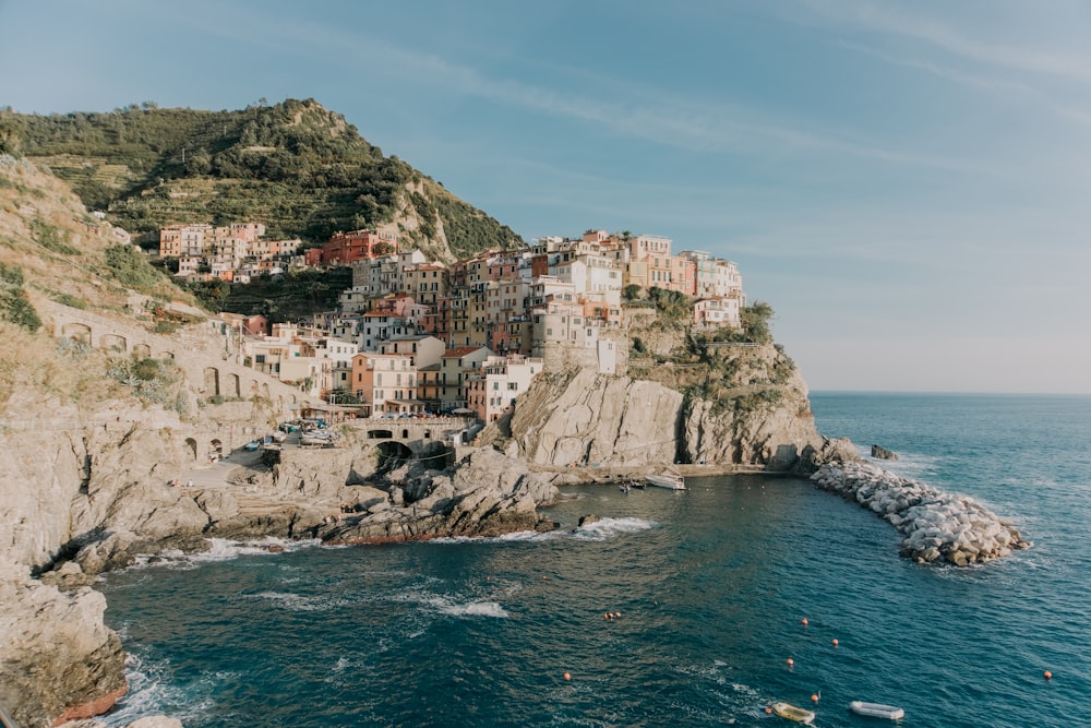 white and brown concrete houses on brown rock formation beside sea during daytime