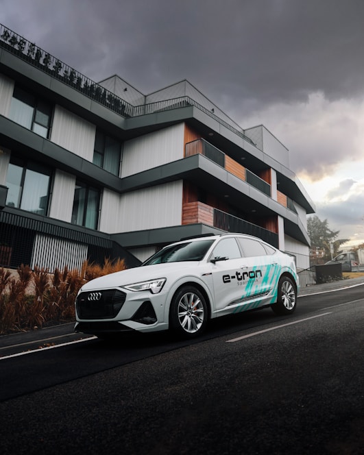 A sleek, modern electric car parked in front of a minimalist black and white building with blue accents.
