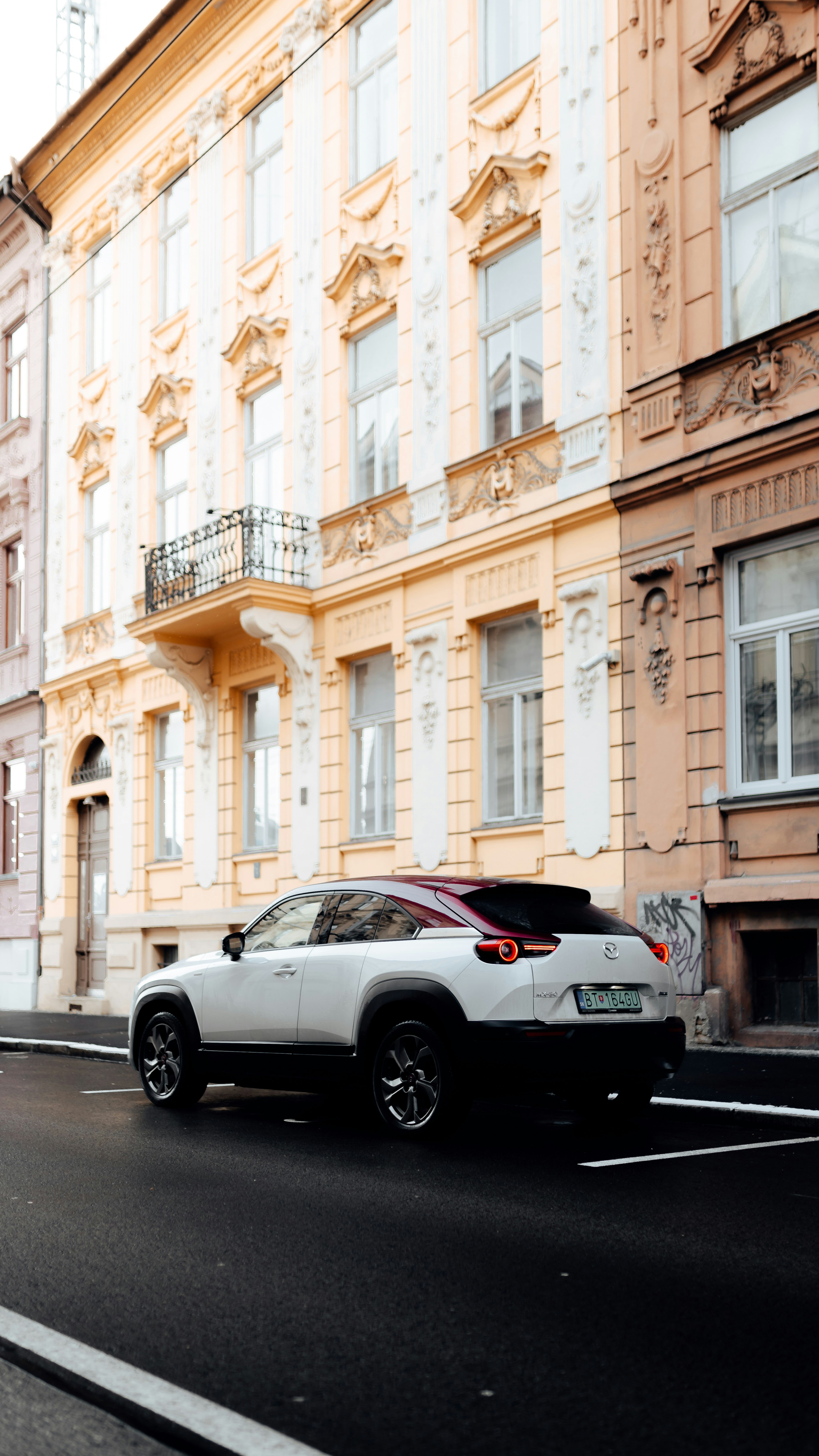 white coupe parked beside white concrete building during daytime