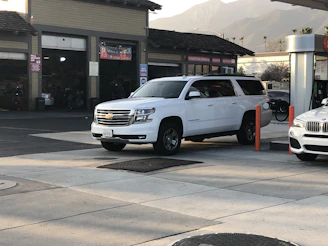 A professional driver assisting a family with luggage beside a Chevrolet Suburban.