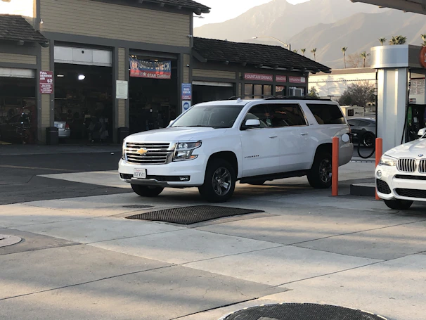 A professional driver assisting a family with luggage beside a Chevrolet Suburban.
