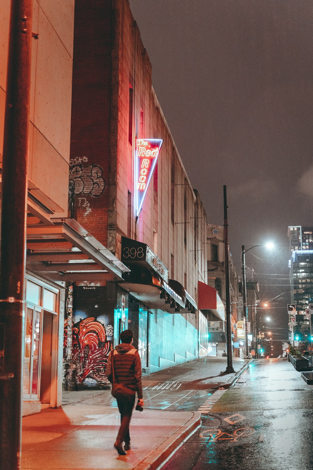 man in red jacket sitting on chair near store during night time