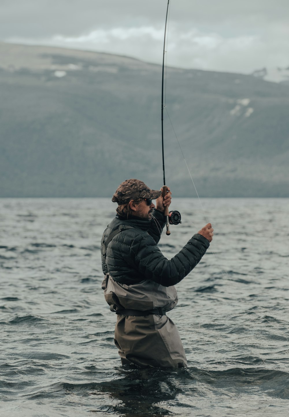 man in black jacket and brown backpack fishing on sea during daytime