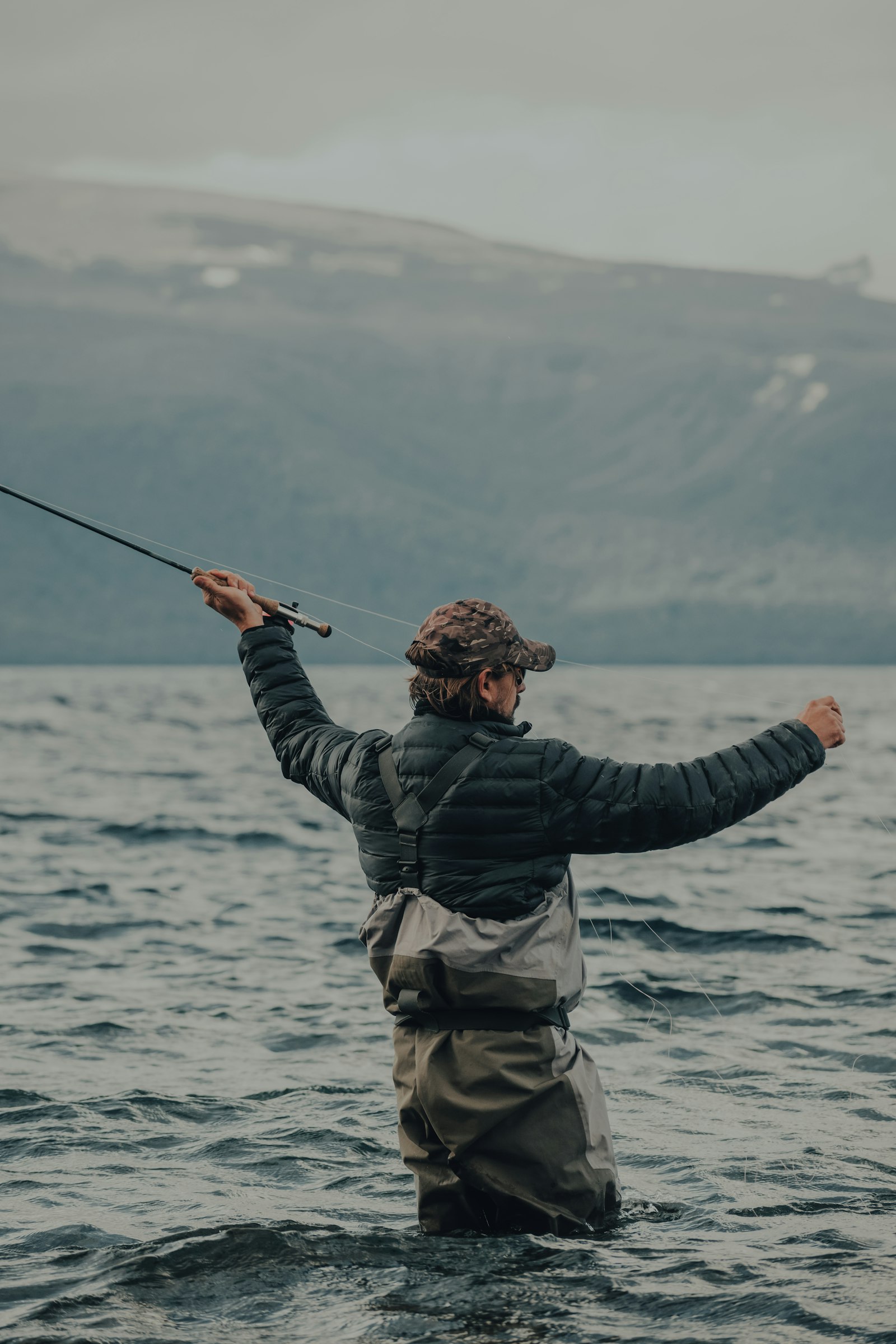 Fly fisherman casting on open flat water — beginner-friendly conditions