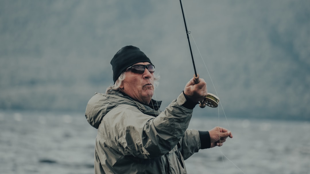 man in gray jacket holding fishing rod