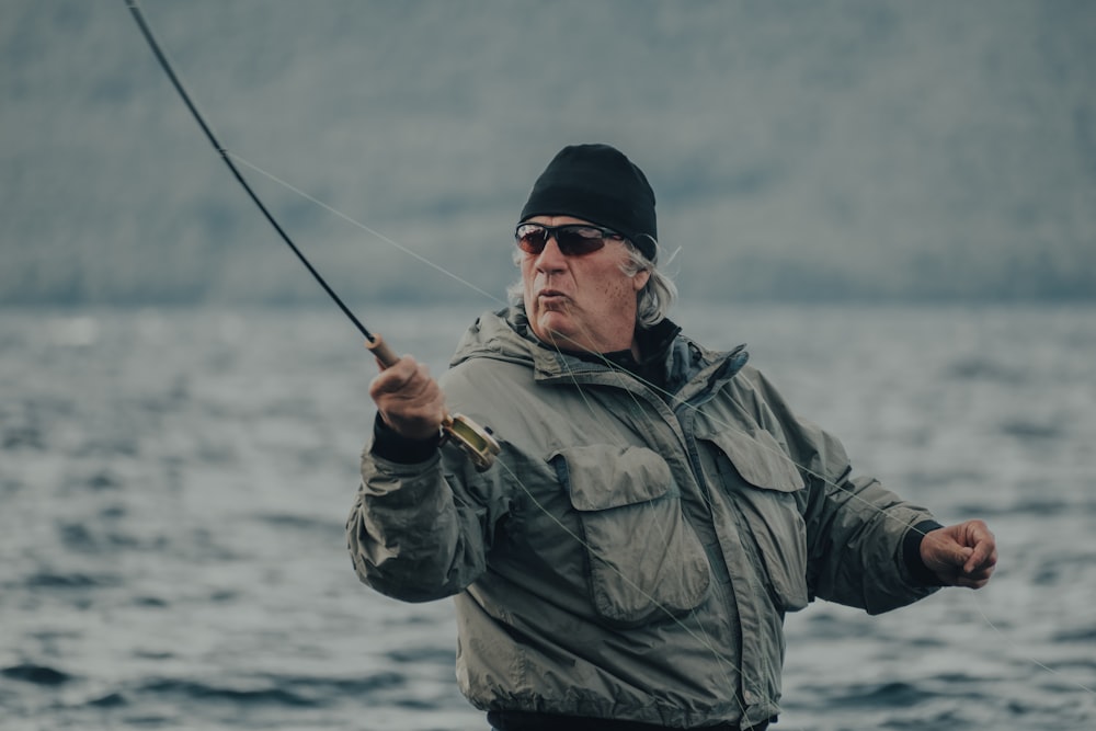 man in black knit cap and green jacket fishing during daytime