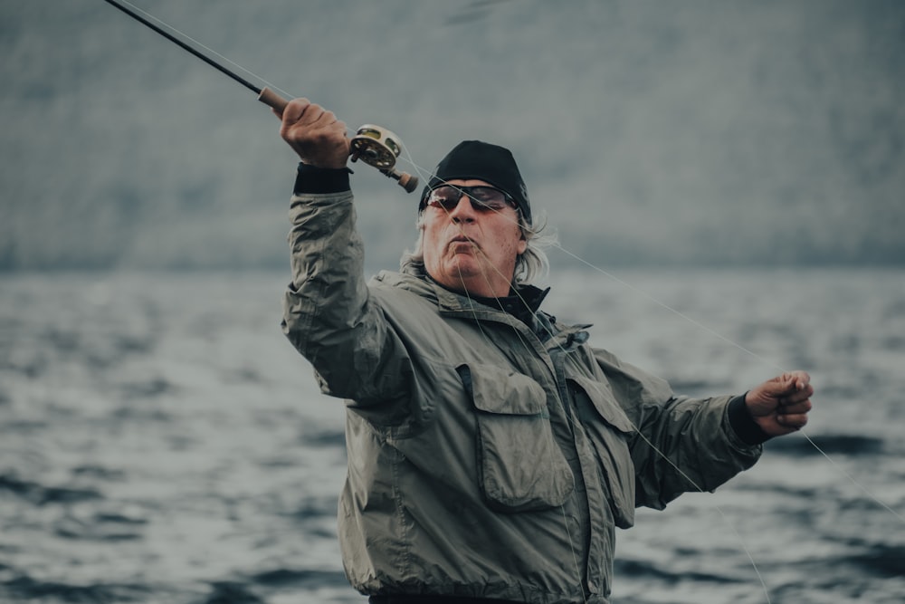 man in gray jacket holding fishing rod