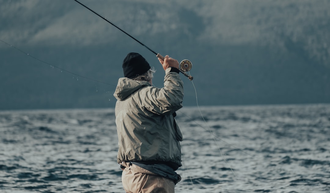 man in brown jacket fishing on sea during daytime