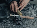 Close-up of hands carefully wrapping carbon fiber strands around a fishing rod blank