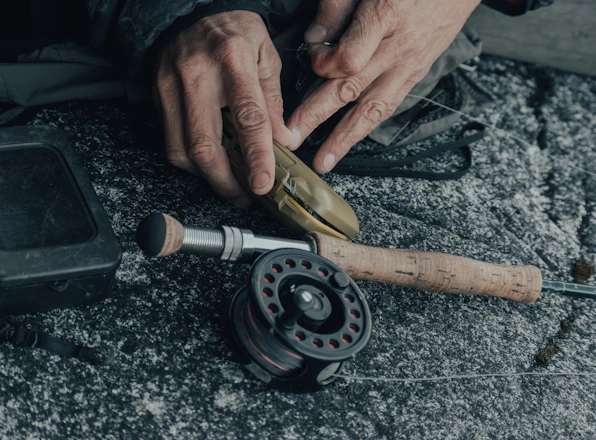 Close-up of a craftsman assembling a custom high-end fishing rod in a bright workshop.