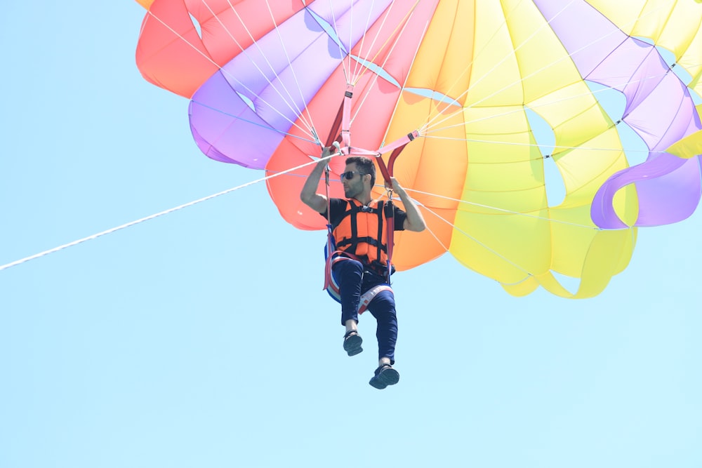 man in black and red jacket and blue denim jeans riding yellow parachute