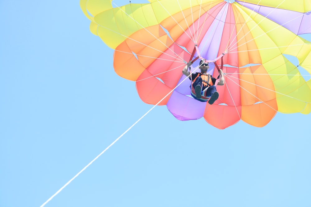 man in black jacket and blue pants riding yellow and red parachute