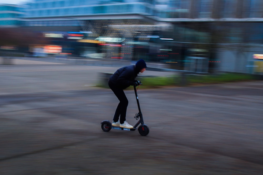 man in black jacket riding black kick scooter on road during daytime