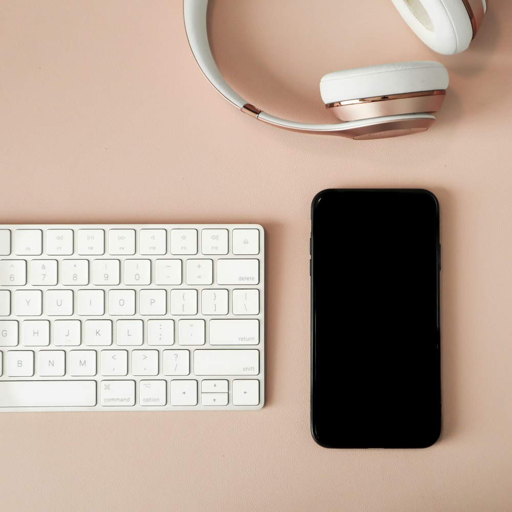 iPhone 7 negro junto al teclado Apple blanco y el mouse de computadora inalámbrico blanco
