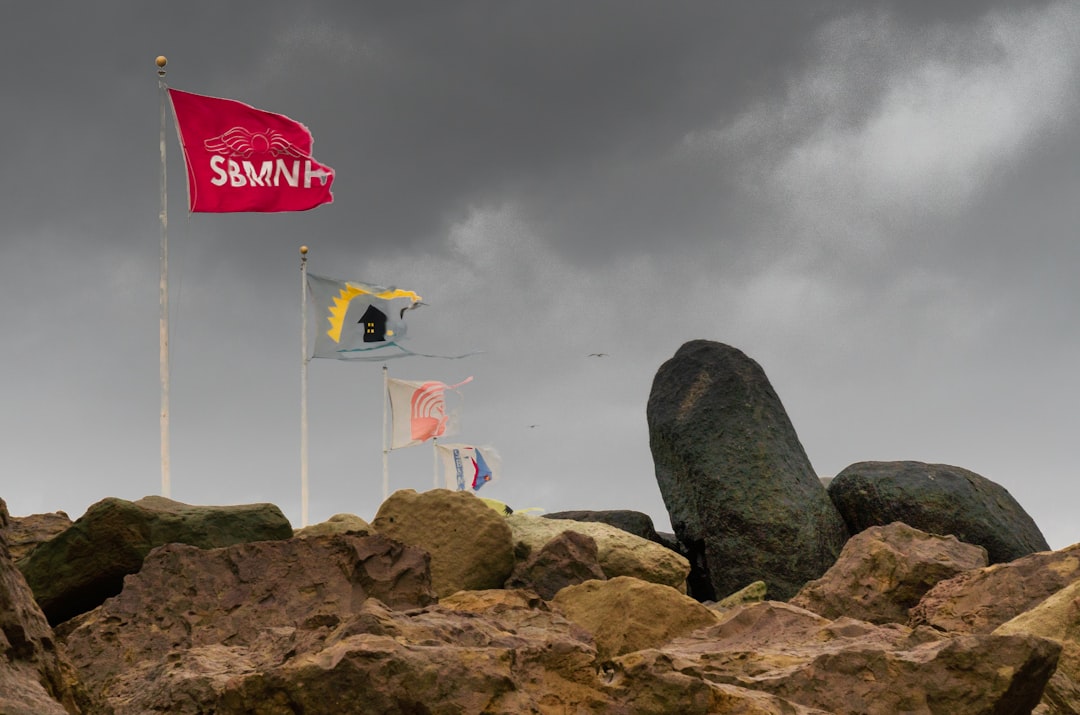 brown rock formation with flag of us a on top under white clouds during daytime