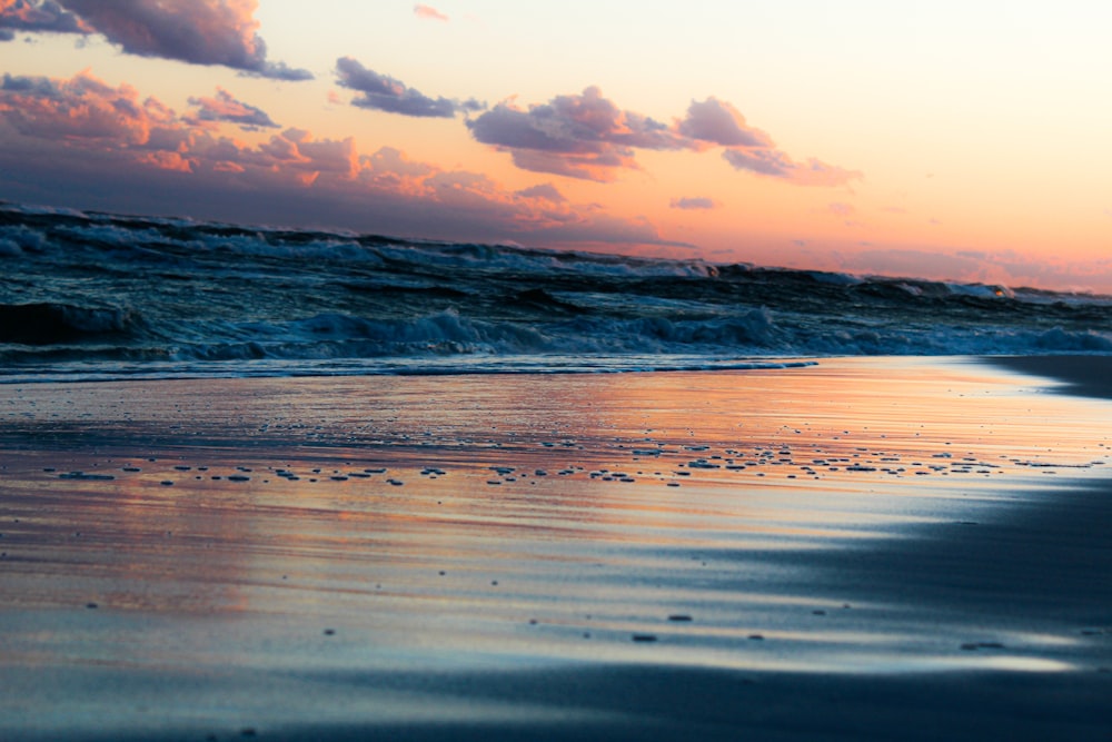 ocean waves crashing on shore during sunset