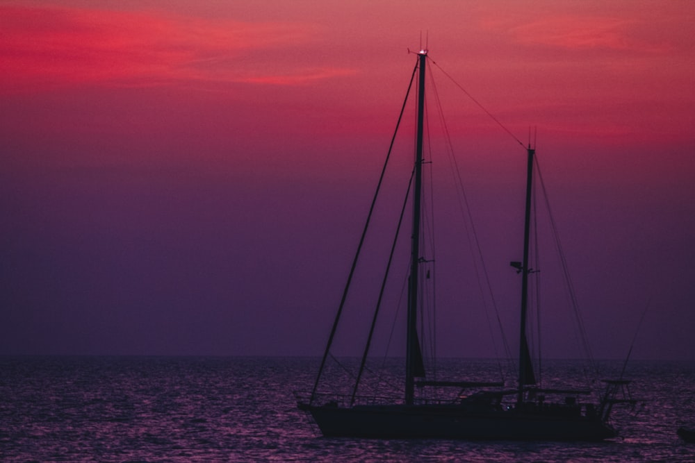 silhouette of sail boat on sea during sunset