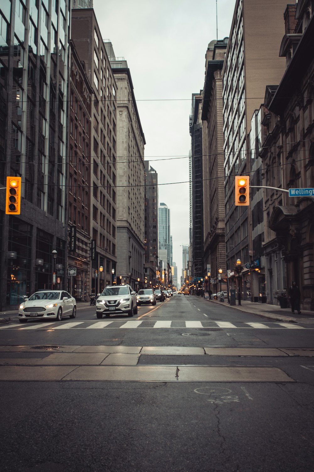 cars parked on side of the road in between high rise buildings during daytime