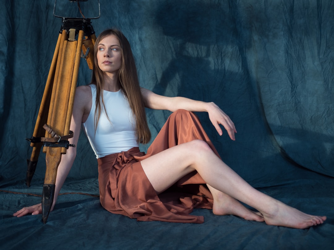 woman in white tank top and red skirt sitting on black textile