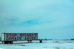 white and red wooden signage on snow covered ground during daytime