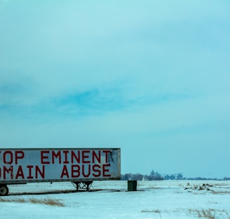 white and red wooden signage on snow covered ground during daytime