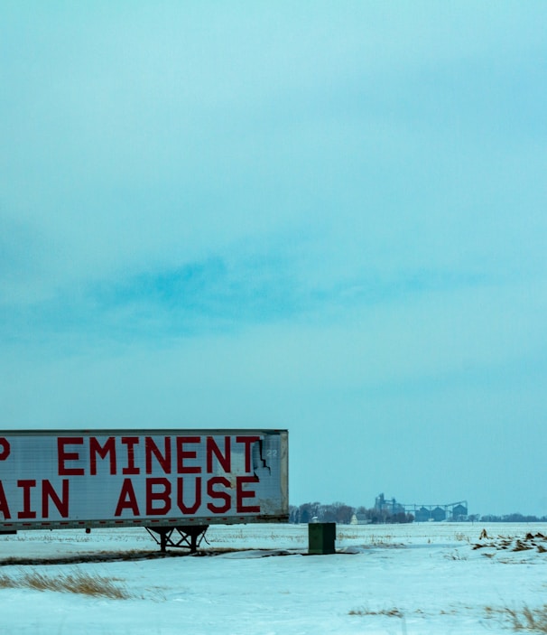 white and red wooden signage on snow covered ground during daytime