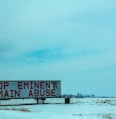 white and red wooden signage on snow covered ground during daytime