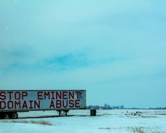 white and red wooden signage on snow covered ground during daytime