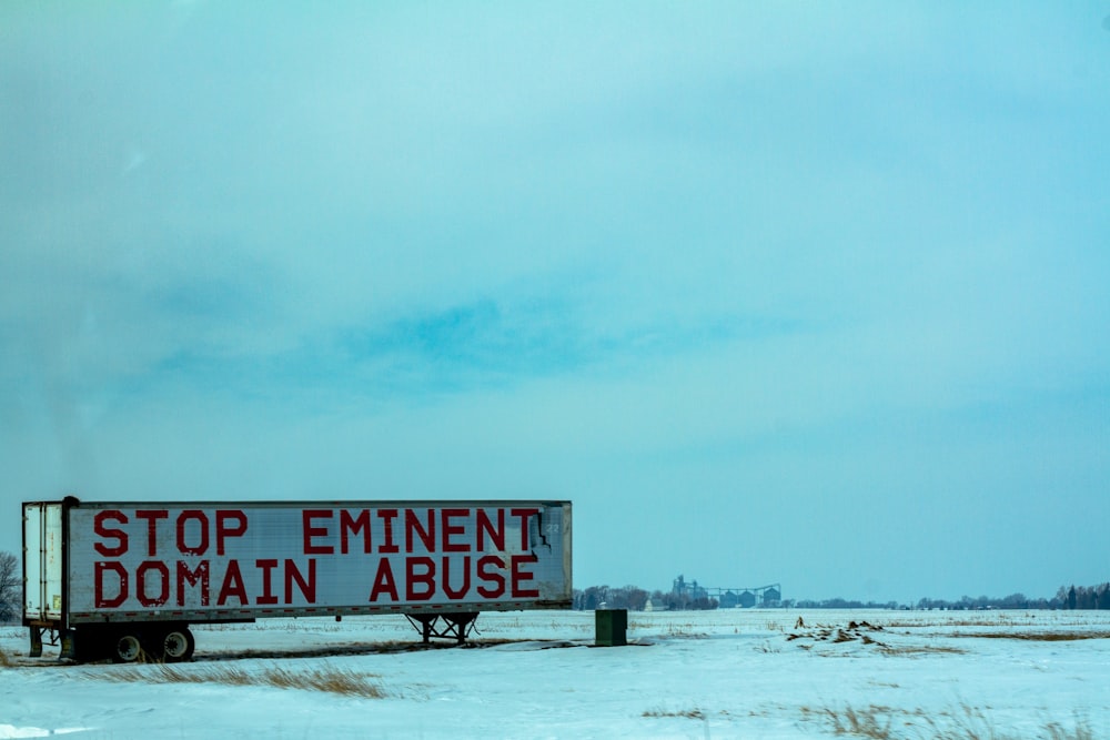 white and red wooden signage on snow covered ground during daytime