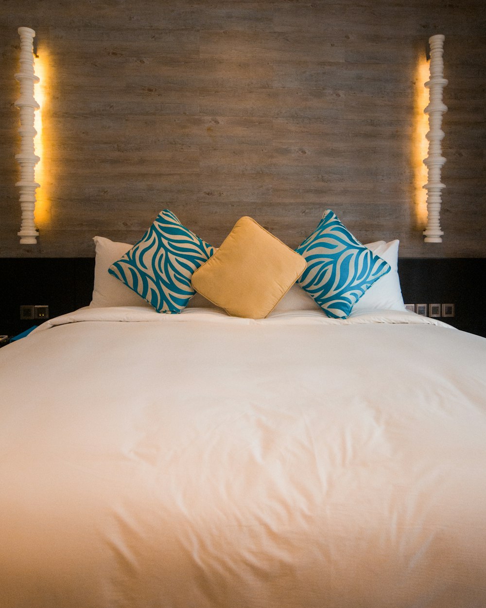 white bed with blue and yellow throw pillows