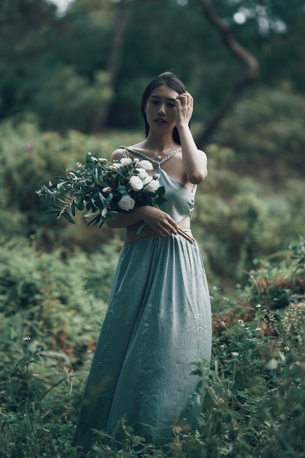 woman in white and blue dress holding white flowers