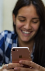 woman in blue and white plaid shirt holding gold iphone 6