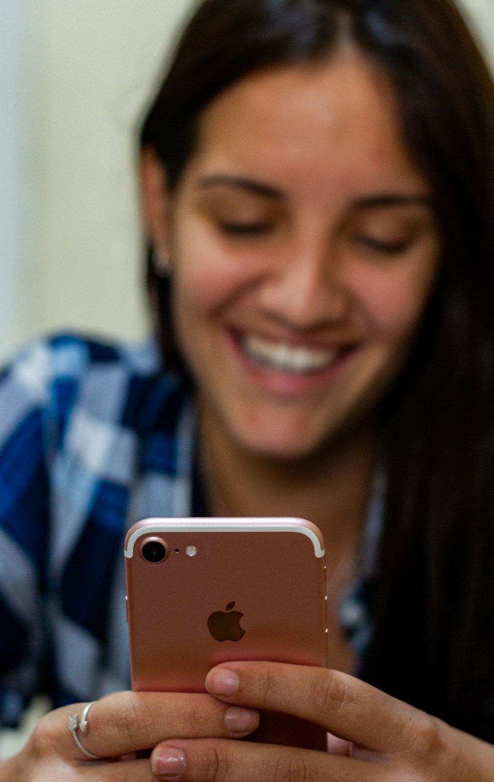 woman in blue and white plaid shirt holding gold iphone 6