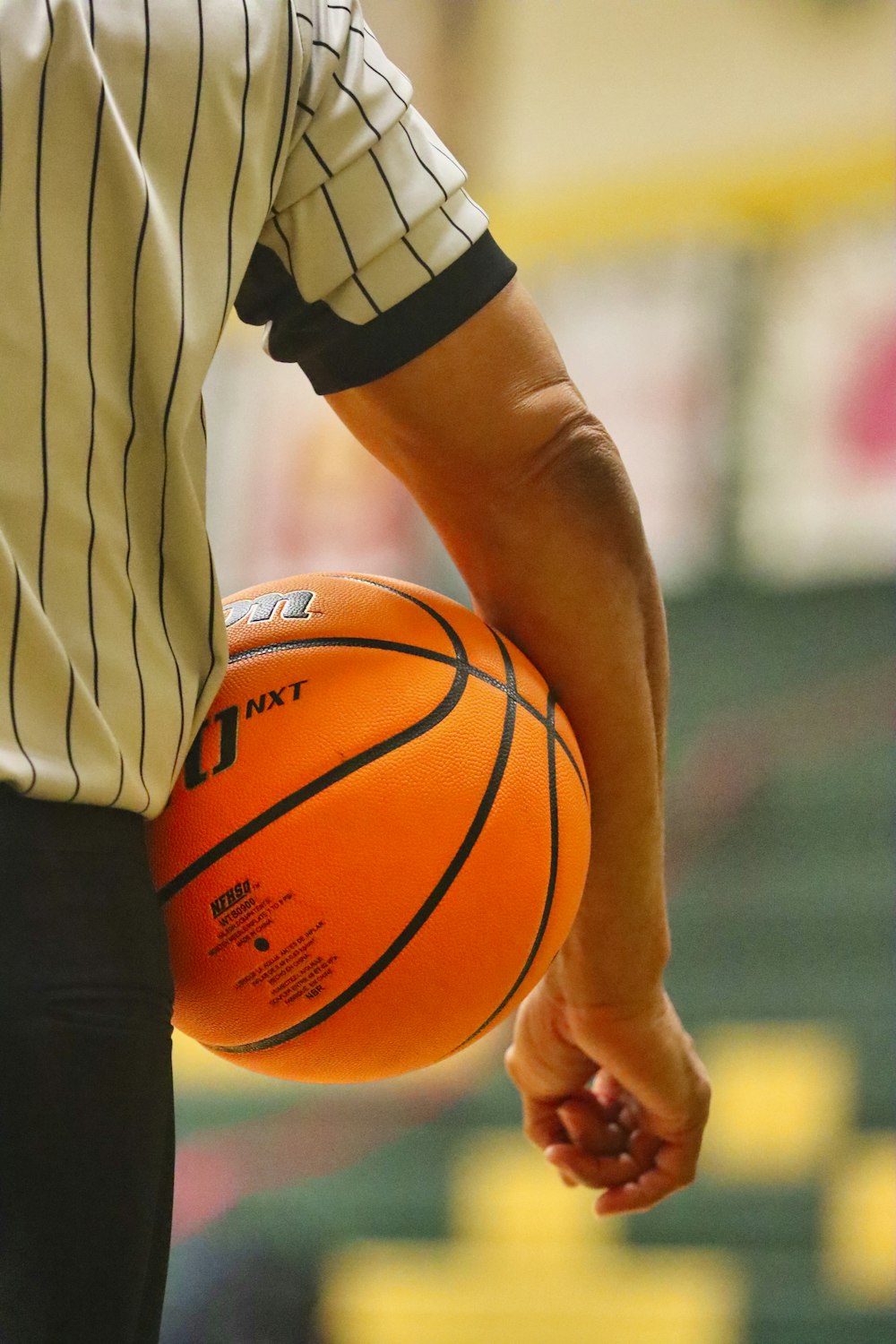 Persona sosteniendo una pelota de baloncesto marrón durante el día