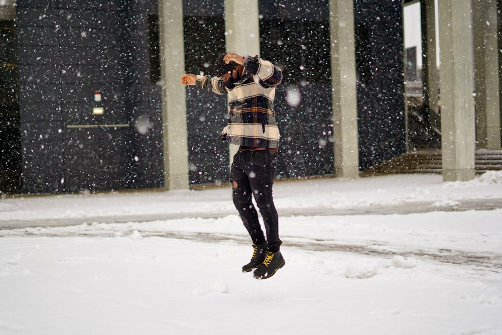 man in black and white plaid dress shirt and black pants standing on snow covered ground
