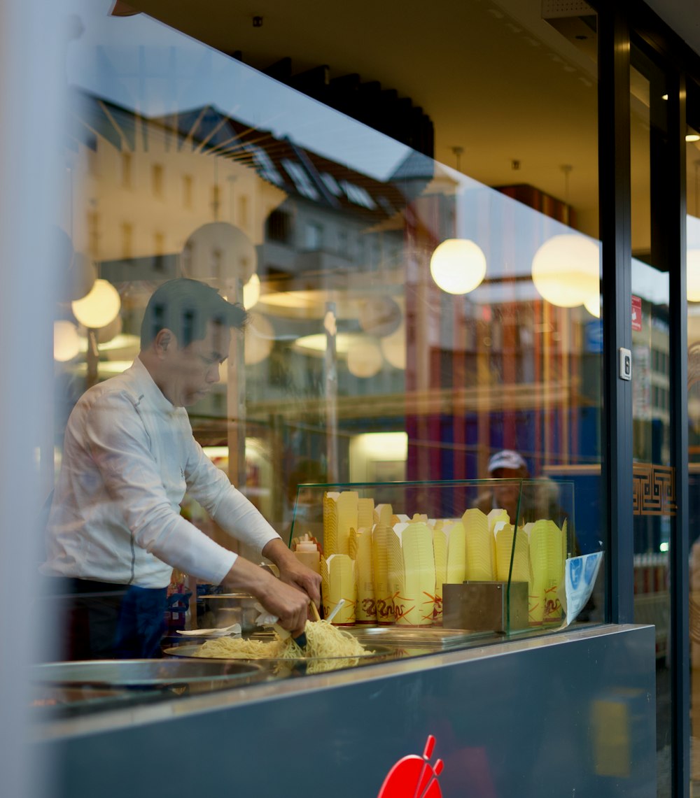 man in white dress shirt and black pants standing in front of glass window