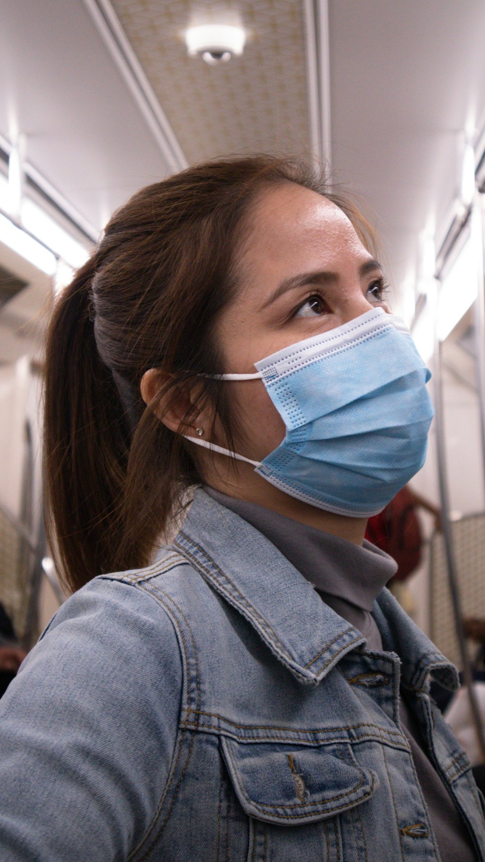 woman in blue denim jacket wearing white face mask